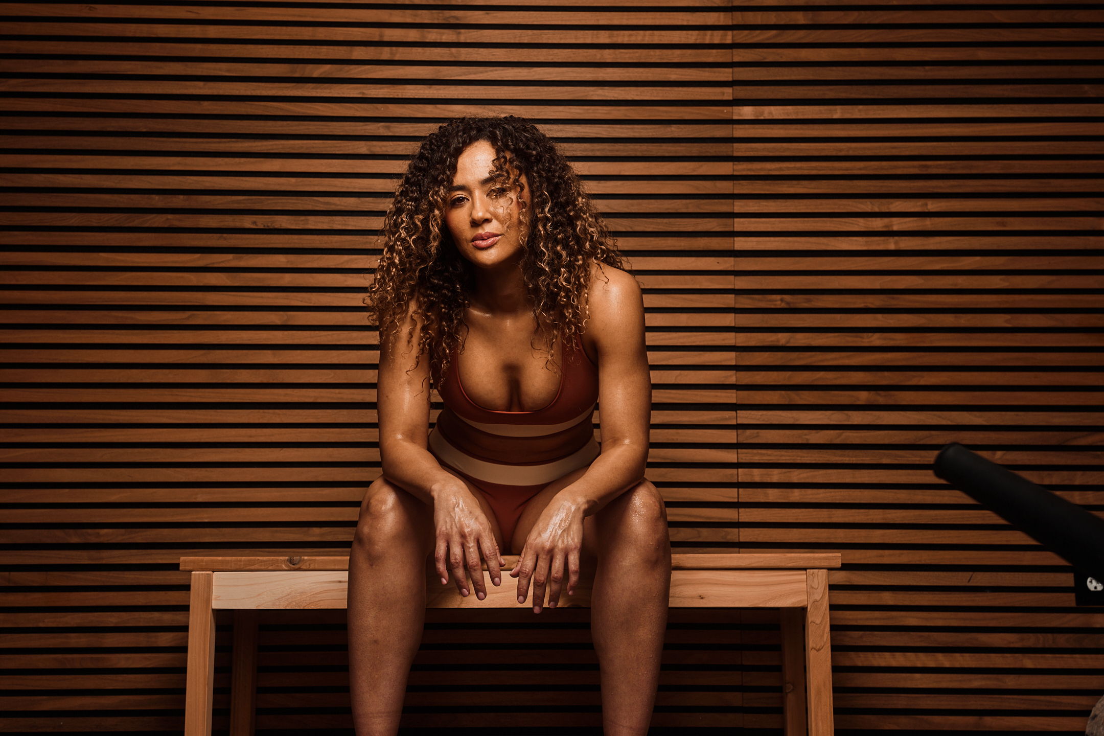 Athlete sitting in a sauna recovery studio with warm wood-paneled walls